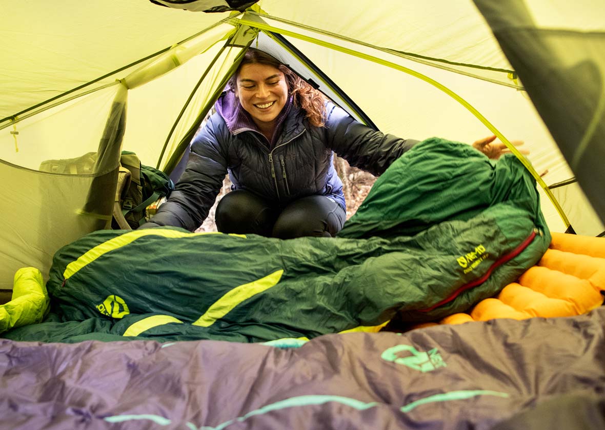 Green Nemo sleeping bag being rolled out inside a tent